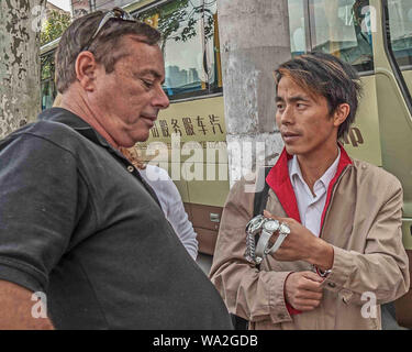 Shanghai, Chine. 30Th Oct, 2006. Un des marchands ambulants Chinois propose des montres pour vendre à un homme touriste. Credit : Arnold Drapkin/ZUMA/Alamy Fil Live News Banque D'Images