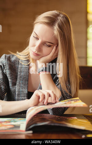 Happy young woman choisir manger au café avec le livret à la main menu Banque D'Images