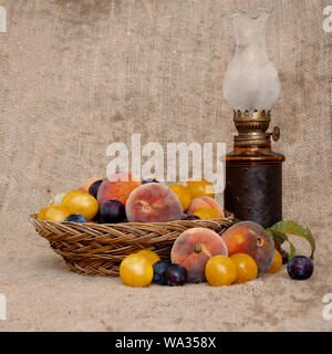 Fruits du patrimoine à l'ancienne à partir d'un verger abandonné depuis longtemps dans un vieux bol en osier, avec lampe à huile sur toile vintage. La vie encore. Banque D'Images