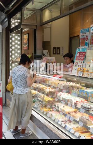 Une japonaise le choix de gâteaux dans un magasin, Shibuya, Tokyo, Japon Banque D'Images