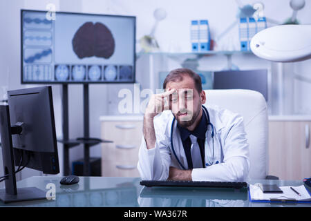 Portrait de jeune scientifique surchargé dans le laboratoire de l'hôpital. Médecin ayant un mal de tête après une longue journée à l'hôpital. Banque D'Images