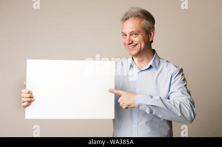 Mature man holding blank board et en pointant sur elle Banque D'Images
