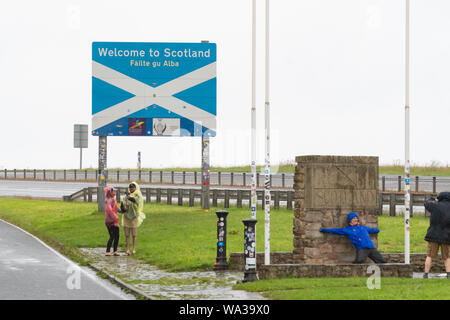 Les touristes dans la pluie en tenant vos autoportraits sur la frontière de l'Écosse quitter l'Angleterre sur l'A1 près de Berwick, Ecosse, Royaume-Uni Banque D'Images