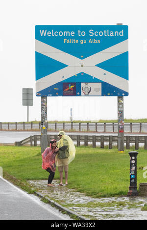 Les touristes dans la pluie en tenant vos autoportraits sur la frontière de l'Écosse quitter l'Angleterre sur l'A1 près de Berwick, Ecosse, Royaume-Uni Banque D'Images