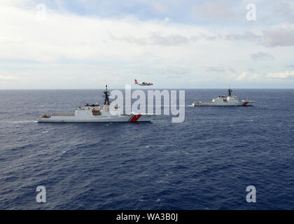 Une station barbiers HC 130 Point d'équipage Hercules survole le garde-côte (WMSL 757 Midgett) et Kimball (WMSL 756) au large d'Oahu, Hawaï, le 16 août 2019. Le Midgett rejoint le Kimball comme la deuxième coupe-homeported la sécurité nationale à Washington. (U.S. Photo de la Garde côtière canadienne par le maître de 3e classe Matthew West/libérés) Banque D'Images