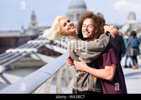 Heureux couple hugging par Millennium Bridge, Tamise, Londres. Banque D'Images