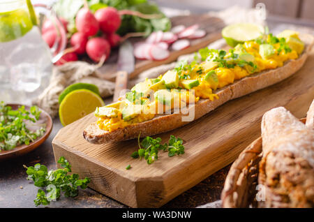 Bio œufs brouillés sur baguette française rustique avec des herbes fraîches et de l'avocat Banque D'Images