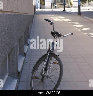 Plan vertical d'une bicyclette grise garée sur le piéton zone près d'un mur Banque D'Images