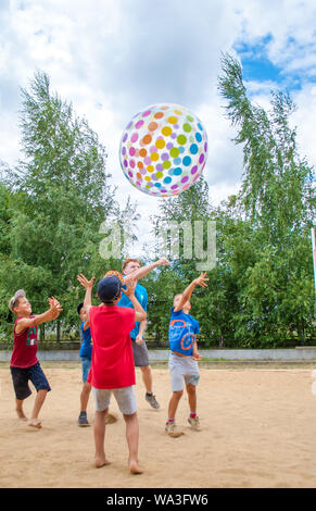 Odesa rgn. L'Ukraine, le 15 juillet 2018 : les garçons jouant avec une grande balle de couleur, le jetant à travers le filet dans le camp d'été. Banque D'Images