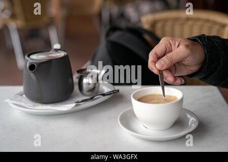 Manches longues en remuant la main avec tasse de café avec une cuillère. Banque D'Images