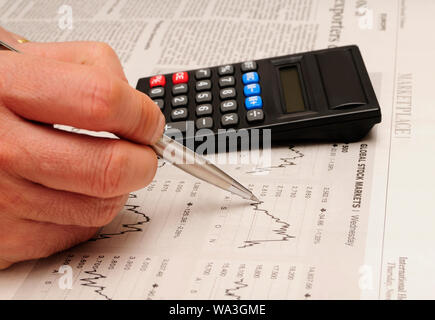Homme main tenant un stylo avec une calculatrice et d'étudier les marchés boursiers graphiques, concept d'investissement Banque D'Images