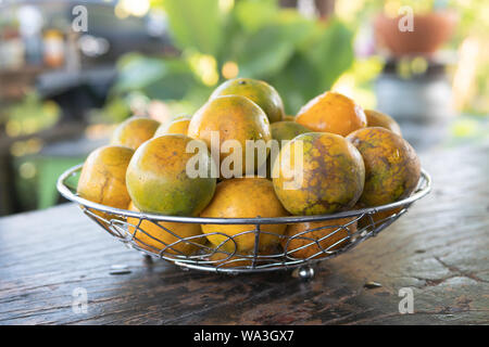 Close up la mandarine dans un panier de métal de l'argent placé sur une table en bois avec arrière-plan flou Banque D'Images