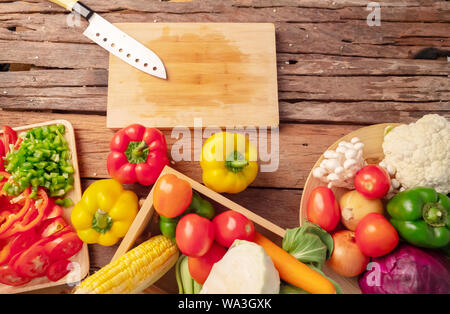 Vue de dessus un couteau sur la planche à découper, vide. Divers légumes placés sur une table en bois qui beaucoup de fibres et d'avantages pour la santé. Banque D'Images
