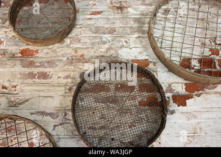 Quatre grilles de jardinage en métal vintage ou devinettes accrochée à un mur de brique rouge blanc. Banque D'Images