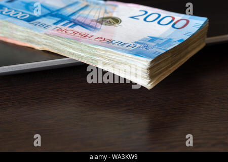 Les paiements pour le travail informatique concept. Pile de roubles russes lay sur clavier d'ordinateur portable. Table en bois brun foncé avec l'exemplaire de l'espace. Haut angle view. Un banknot Banque D'Images