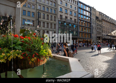 Genève, Suisse - Juillet, 08, 2019 : le lac de Genève et la ville sur une journée ensoleillée.Fontaine à la place du Molard et la Rue du Marche. Banque D'Images