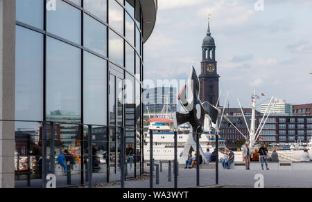 Hambourg, Allemagne. 14Th Aug 2019. Les passants s'asseoir à la sculpture 'La Grande fleur qui marche' (M) par l'artiste Fernand Léger au musical pier "Roi des Lions". Dans l'arrière-plan vous pouvez voir l'église principale (St Michel 'Der Michel', dans l'arrière-M). Photo : Markus Scholz/dpa/Alamy Live News Banque D'Images