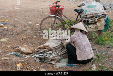 Vietnamienne waring une cône traditionnel hat travaillant comme un nettoyant pour le recyclage des boîtes en papier de préparation Banque D'Images