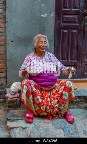 Smiling asian senior women est assis sur un trottoir et filage de la laine est Banque D'Images