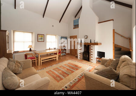 Maison moderne de l'intérieur spacieux et lumineux avec conversion salle de séjour spacieuse, haute de plafond poutre de toit exposées et en brique de cheminée avec poêle à bois. Banque D'Images