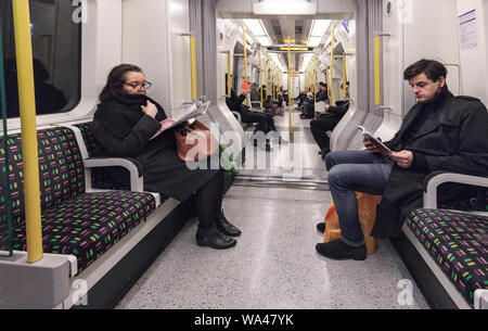 La lecture et les passagers assis de l'autre ignorant en silence sur une ligne de métro de Londres train vers l'ouest du district de Earls Court Banque D'Images