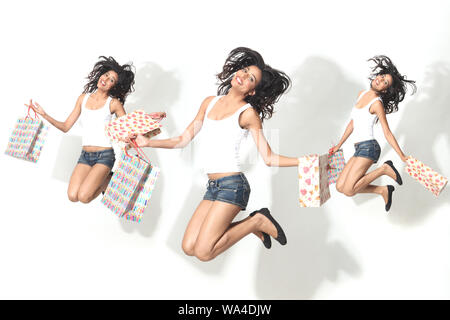 Plusieurs images d'une jeune femme sautant dans l'air avec des sacs d'achats Banque D'Images