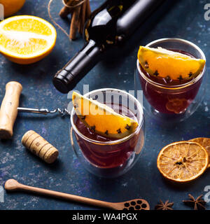 Deux verres de vin chaud avec Clint tranches d'orange parmi les ingrédients pour la cuisine et une bouteille de vin Banque D'Images