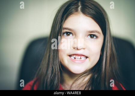 Close up de l'enfant en souriant avec des dents manquantes et les yeux bruns Banque D'Images