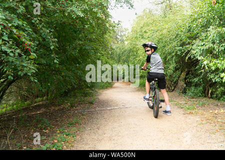 School boy dans le casque de protection riding bike dans le parc Banque D'Images