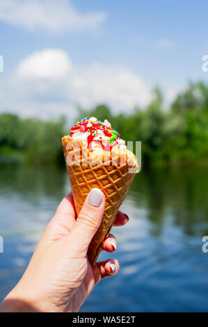 Concept créatif drôle de cône avec de la crème glacée couvertes et parsemé Nutrifer. La crème glacée corne sur le fond de la rivière. La crème glacée en corne na Banque D'Images