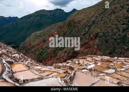 Anciennes mines de sel, Salineras de Maras : des milliers de petits bassins creusés dans le flanc d'une montagne avec des sommets enneigés de montagnes Urubamba sur la zone Banque D'Images