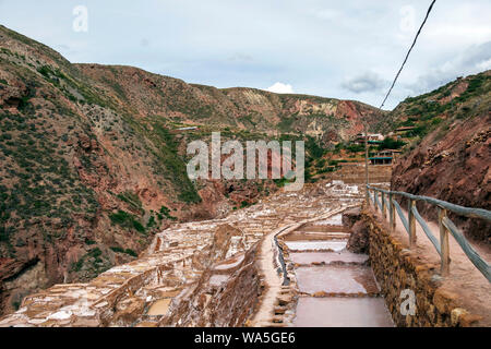 Anciennes mines de sel, Salineras de Maras : des milliers de petits bassins creusés dans le flanc d'une montagne avec des sommets enneigés de montagnes Urubamba sur la zone Banque D'Images