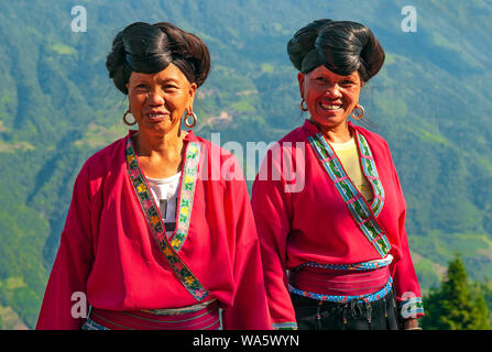 Les femmes aux cheveux longs souriant du groupe ethnique Yao par les rizières en terrasses de Longsheng Ping An dans la province du Guangxi, Chine. Banque D'Images