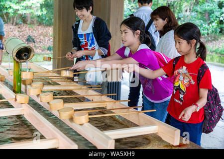 Tokyo, Japon - 14 juin 2015 - Les touristes et les visiteurs de se laver les mains et la bouche à la fontaine d'eau avant d'entrer dans le sanctuaire à Tokyo, Japon, le Ju Banque D'Images