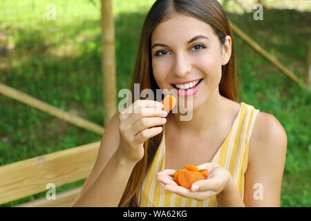 Young woman eating fruits secs dans le parc. Concept d'aliments sains. Banque D'Images