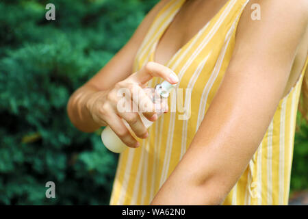 L'insectifuge. Anti insectes bug spray. Femme de pulvériser un insectifuge sur la peau Mise en plein air à l'aide de la nature flacon pulvérisateur. Banque D'Images