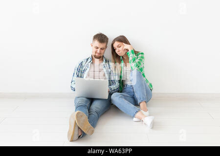 Jeune femme charmante et a smiling man regardez les magasins en ligne en utilisant un ordinateur portable pour acheter un appartement neuf dans la plomberie. Concept de réparation et de pendaison. Banque D'Images