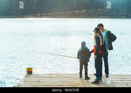 Père et Mère avec enfant Garçon jouant avec de l'eau banc près de Riverside. Banque D'Images