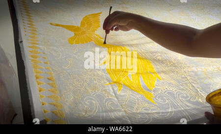 Ubud, INDONÉSIE - juin, 19, 2017 : portrait d'un artiste peignant un oiseau jaune sur tissu batik à Bali Banque D'Images