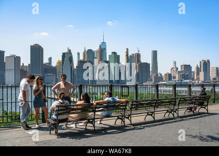 Les jeunes New York, vue en été d'un groupe d'amis se détendre sur Brooklyn Heights Promenade avec le bas Manhattan city skyline, NEW YORK, USA visible Banque D'Images