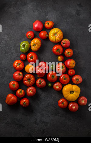 Lettre A fait avec tomates mûres sur un fond noir, creative télévision jeter des aliments sains concept. Banque D'Images