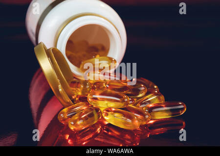 Des capsules d'huile de poisson à l'oméga 3 et de vitamine D dans une bouteille de verre sur la texture, l'alimentation saine concept, Close up shot. Banque D'Images