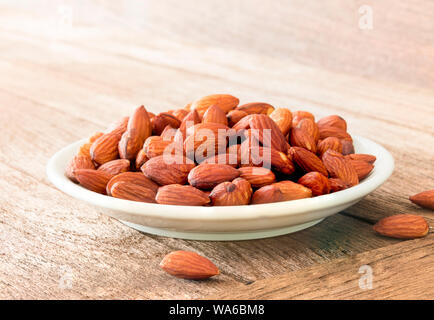 Les amandes dans le bol brun sur fond de bois Banque D'Images