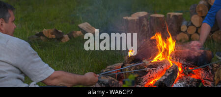 Deux amis sont assis autour d'un feu de camp et tout simplement se détendre Banque D'Images