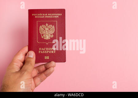 Passeport international russe dans la main des hommes sur fond rose Banque D'Images