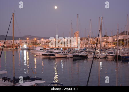 Pleine lune sur le port, avec des bateaux dans le port de plaisance dans l'avant-plan. Tôt le matin, la lumière. Banque D'Images