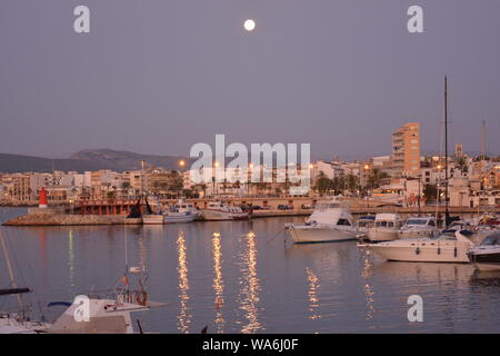 Pleine lune sur le port, avec des bateaux dans le port de plaisance dans l'avant-plan. Tôt le matin, la lumière. Banque D'Images