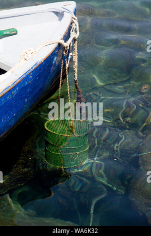 Un panier de pêche traditionnel et écologique suspendu à l'arc d'un petit bateau, avec espace pour la copie Banque D'Images