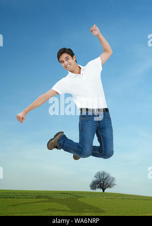 Jeune homme de sauter dans l'air et souriant Banque D'Images