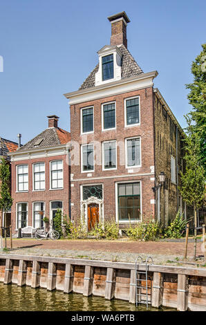 Harlingen, Pays-Bas, le 26 juillet 2019 : deux maisons du canal, une grande et une petite, avec banc, location et la végétation des trottoirs Banque D'Images